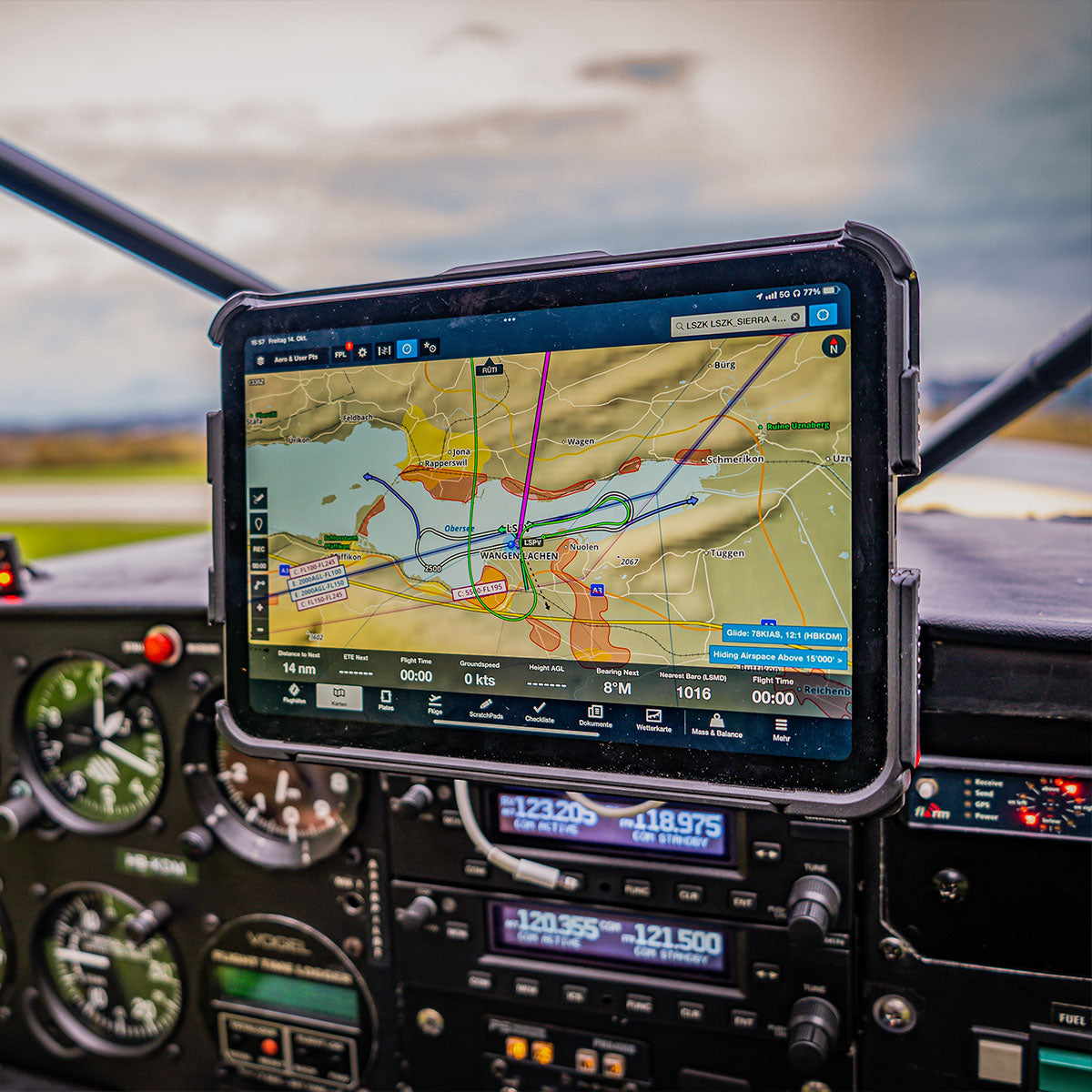 A cockpit view of an airplane featuring an electronic flight display with a navigation map on a tablet fixed to the dashboard. Surrounding the tablet are various flight instruments and controls, indicating altitude, speed, and other essential flight data.